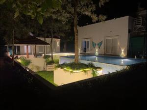 a house with a swimming pool at night at Serenity Farm Stay in Hampāpura