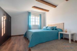 a bedroom with a bed with blue sheets and a window at Casa Eira de Arriba - by entreRías in Cangas de Morrazo