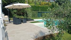 a patio with an umbrella and a swimming pool at Margot Ca Bianca Dormelletto Lago Maggiore in Dormelletto