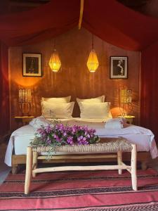 1 dormitorio con 1 cama con flores en un banco en La Ferme Berbere Adult only, en Marrakech