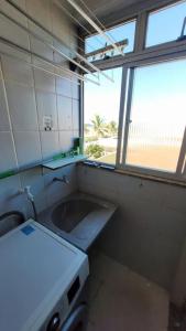 une petite cuisine avec un évier et une fenêtre dans l'établissement Lindo apto de frente para o mar, à Serra