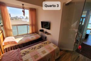 une chambre d'hôtel avec deux lits et une fenêtre dans l'établissement Lindo apto de frente para o mar, à Serra