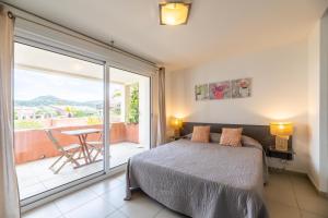 a bedroom with a bed and a balcony with a table at Les Alizés Résidence & Spa in LʼÎle-Rousse +160 photos