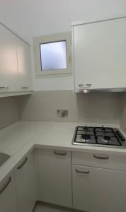 a white kitchen with a stove and a window at Hotel De La Playa in Velipojë