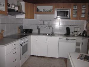 a kitchen with white cabinets and a sink and a microwave at Apartment Holmsland in Hvide Sande