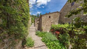 Une allée dans un vieux bâtiment en pierre avec des fleurs dans l'établissement Il Portico, à Gaiole in Chianti