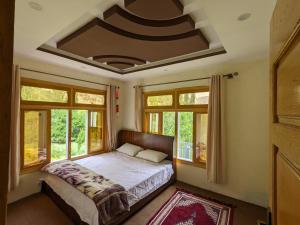 a bedroom with a bed in a room with windows at Alpine Resort Khaplu in Khaplu