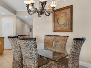 a dining room with a glass table and a chandelier at San Remo Condominium 201 by Newman-Dailey in Santa Rosa Beach