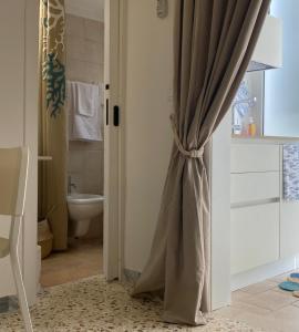 a bathroom with a shower curtain and a toilet at Ostuni Ayla Apartments in Villanova di Ostuni +133 photos