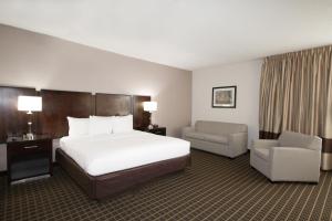a hotel room with a large bed and a chair at Clarion Inn & Suites Miami International Airport in Miami