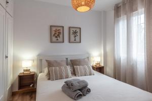 a bedroom with a white bed with two towels on it at Renovated apartment on beachside with pool in Nerja