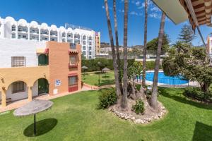 a view of a resort with a pool and palm trees at Renovated apartment on beachside with pool in Nerja