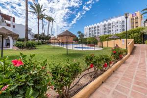 a resort with a garden and a swimming pool at Renovated apartment on beachside with pool in Nerja