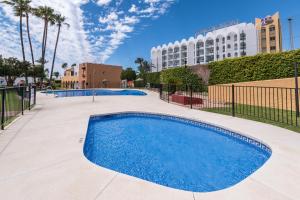 a swimming pool with a hotel in the background at Renovated apartment on beachside with pool in Nerja