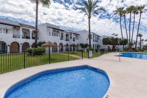 a swimming pool in front of a house with palm trees at Renovated apartment on beachside with pool in Nerja