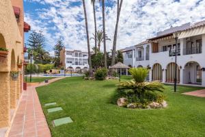 a yard with palm trees and a building at Renovated apartment on beachside with pool in Nerja
