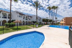 a swimming pool in front of a house and palm trees at Renovated apartment on beachside with pool in Nerja