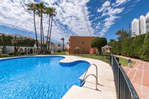 a swimming pool in a resort with palm trees at Renovated apartment on beachside with pool in Nerja
