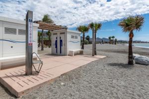 a building on the beach with palm trees and a sign at Renovated apartment on beachside with pool in Nerja