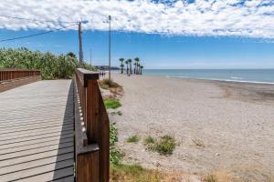 a boardwalk on a beach with palm trees and the ocean at Renovated apartment on beachside with pool in Nerja