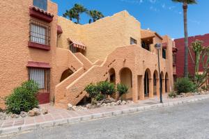 an orange brick building with a palm tree next to a street at Renovated apartment on beachside with pool in Nerja