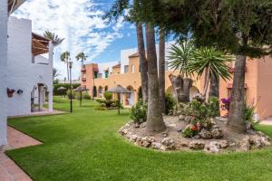 a yard with palm trees and a building at Renovated apartment on beachside with pool in Nerja