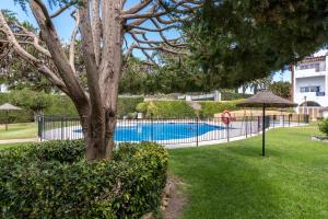 a fence with a tree and a swimming pool at Renovated apartment on beachside with pool in Nerja