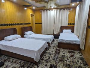 two beds in a room with yellow walls at Alpine Resort Khaplu in Khaplu