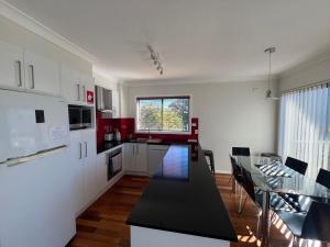 a kitchen with a black counter top and a table at Ocean Retreat in Nambucca Heads