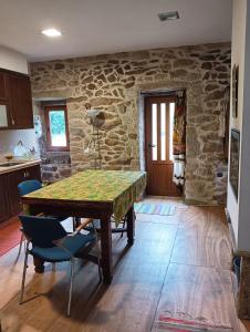 a kitchen with a table and chairs and a stone wall at A Parrula, Mar, río y montaña in Sotomayor