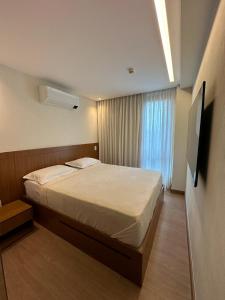 ein Schlafzimmer mit einem großen Bett und einem Fernseher in der Unterkunft Vista Azul Apart Hotel - Suite Vista Pedra Azul in Pedra Azul