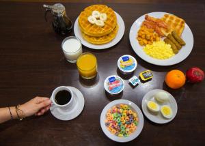 a table with breakfast foods and a person holding a cup of coffee at Clarion Inn & Suites Miami International Airport in Miami