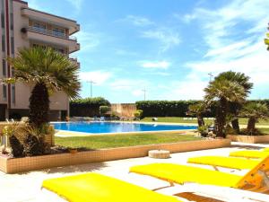 una piscina con tumbonas amarillas y un complejo turístico en Holidays appartment, en Furadouro