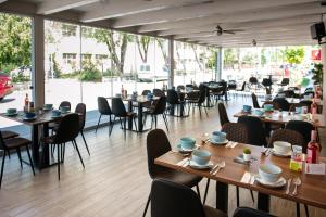 a restaurant with wooden tables and chairs and windows at Turul Boutique Rooms & Apartment in Szarvas