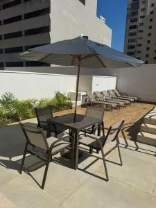 a table and chairs with an umbrella on a patio at Studio Quirino- novo e moderno in Campinas