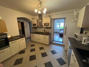a kitchen with white cabinets and a checkered floor at -Self-Check- 4-bedroom family house with heated tub in Levice
