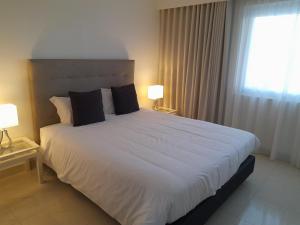 a bedroom with a large white bed with two lamps at Victory Village 2A in Quinta do Lago +44 photos