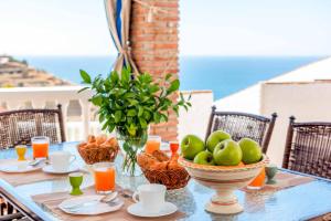 een tafel met een schaal fruit en een vaas met sinaasappels bij Villa Cecilia Sol in Torrox