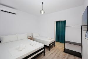 a white room with two beds and a window at Guesthouse Noke in Berat