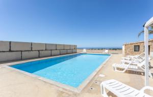 ein Swimmingpool mit Liegestühlen neben einer Backsteinmauer in der Unterkunft Cozy Home In Santa Croce Camerina in Santa Croce Camerina