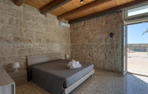 ein Schlafzimmer mit einem Bett und einer Steinwand in der Unterkunft Cozy Home In Santa Croce Camerina in Santa Croce Camerina