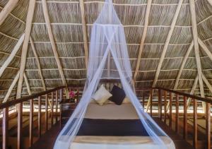 a bed in a thatched room with a mosquito net at Cabañas Linda Vista in Chimo