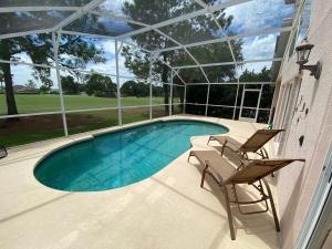 una piscina in una casa con due sedie di 8th Fairway Holiday Home Updated Southern Dunes a Haines City