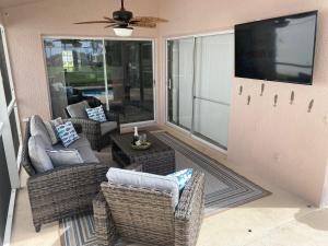 una veranda protetta con sedie in vimini e una TV di 8th Fairway Holiday Home Updated Southern Dunes a Haines City