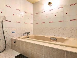 y baño con bañera y paredes de azulejos blancos. en Setouchi Resort Hotel - Vacation STAY 95869v, en Matsuyama