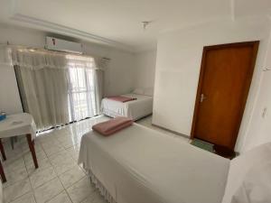 a bedroom with two beds and a table and a window at Hotel Califórnia in Tangara da Serra