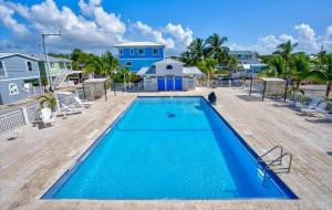 a pool with chairs and a house in the background at Key Largo Paradise in Key Largo