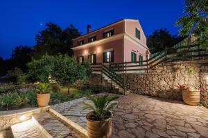 a house with a stone wall and potted plants at Villa Oros in StrinÃ½las