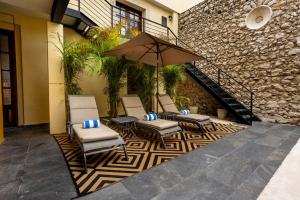 Eine Gruppe Stühle und ein Sonnenschirm auf einer Terrasse in der Unterkunft Kuxtal Hotel Boutique in Mérida