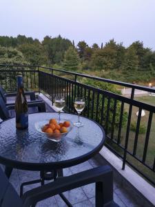 a table with a bowl of oranges and two glasses of wine at Villa Adamidis in Paralía Skotínis +61 photos